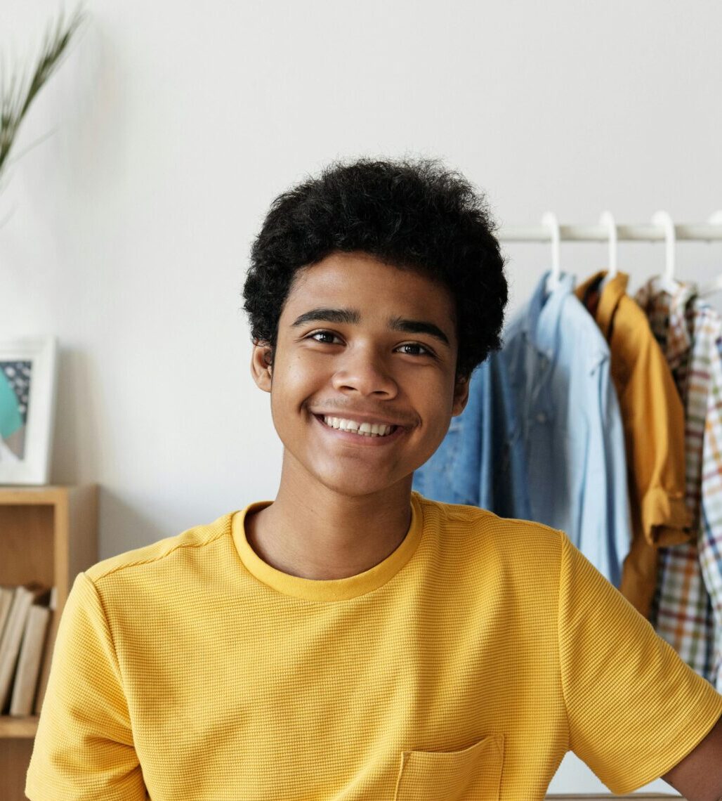 Smiling teenager using a tablet at his desk for online learning at home.